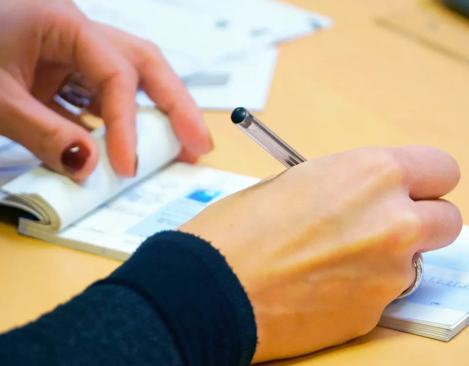 Bir kişinin çek defteri ve kalemle evrak üzerinde not alarak kambiyo takibine itiraz dilekçesi hazırlaması.