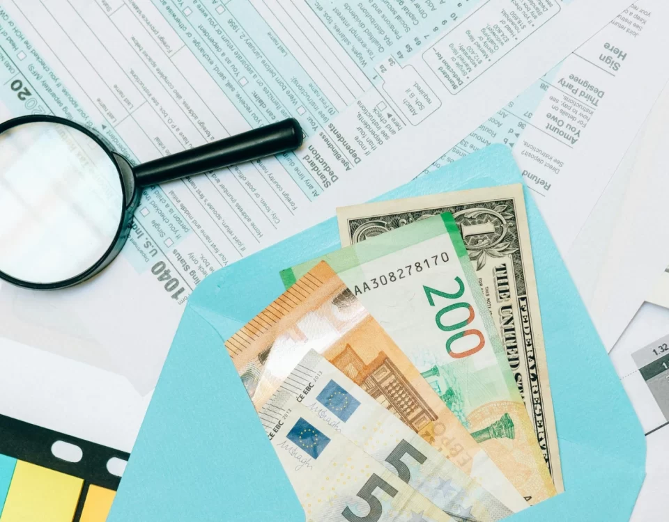 Beyana dayalı tarh sürecini ve ihtirazi kayıtla beyanname verilmesini anlatan görsel; vergi formları üzerinde para zarfı ve büyüteç.