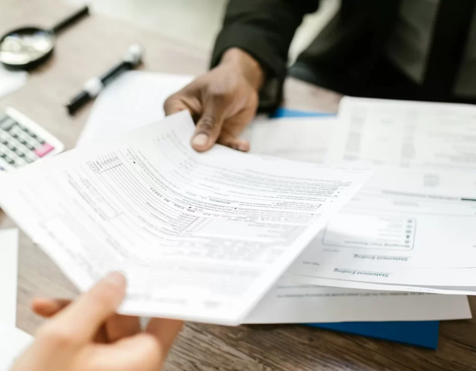 Re’sen tarhiyat ve ceza ihbarnamesine itiraz sürecini anlatan görsel; masa üzerinde vergi evraklarının incelenmesi ve evrak teslimi.