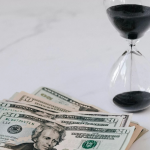 Vergi Borcu Zamanaşımı 1 Vergi alacaklarında zamanaşımı (vergi borcu zamanaşımı) konulu makale görseli; kum saati ve para ile zaman aşımı sürelerini simgeleyen görsel.