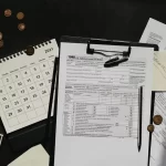 Vergi İncelemesi 1 Vergi incelemesi konulu makale görseli; vergi formları, takvim ve büyüteç ile denetim sürecini simgeleyen masa düzeni.