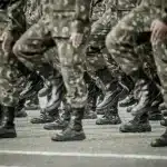 Askerlik Nedeniyle İşten Ayrılma 1 Askeri kamuflaj ve siyah botlarla uygun adım yürüyüş yapan askerler; askerlik nedeniyle işten ayrılma ve kıdem tazminatı sürecini temsil eden görsel.
