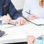 Emeklilik Nedeniyle İş Sözleşmesi Feshi: İşçinin Alacak Hakları 1 Toplantı masasında elindeki fesih belgesini işverene sunan işçi; emeklilik nedeniyle iş sözleşmesi feshi ve kıdem tazminatı sürecini temsil eden ofis görüşmesi.