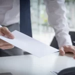 İşverenin Haksız Feshi: 2026 Kapsamlı İşçi Hakları Rehberi 1 İşveren temsilcisi tarafından işçiye uzatılan yazılı fesih bildirimi zarfı. İşverenin haksız feshi durumlarında tebligat anı.