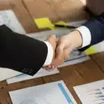 Şirket Birleşme ve Devralma Süreci: 2026 Güncel Kapsamlı Hukuki Rehber 1 Masada şirket birleşme ve devralma sözleşmesi imzalayan iş insanlarının elleri ve önlerindeki resmi evraklar.