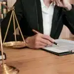 Ticari Sözleşmede Cezai Şart: 2026 Güncel Yargıtay Kararları Işığında Kapsamlı Hukuki Analiz 2 Masasında adalet terazisi bulunan bir hukukçunun veya tacirin, ticari sözleşmede cezai şart hükümlerini içeren hukuki belgeyi dikkatle incelemesi.