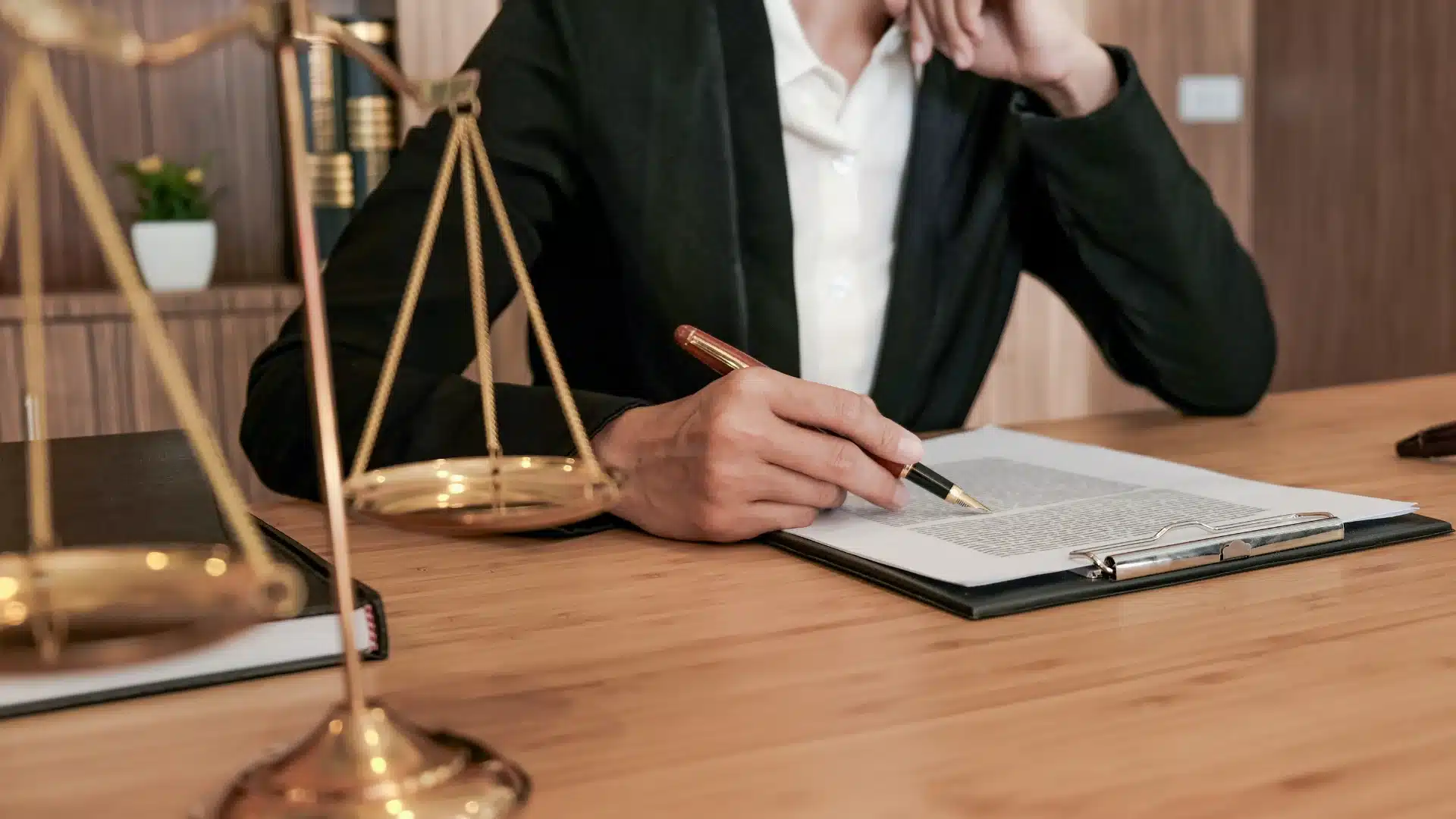 Masasında adalet terazisi bulunan bir hukukçunun veya tacirin, ticari sözleşmede cezai şart hükümlerini içeren hukuki belgeyi dikkatle incelemesi.