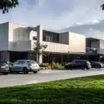Haczedilemeyen Mallar ve Haklar: İİK m. 82 Kapsamında Hukuki Değerlendirme 1 İcra ve İflas Kanunu uyarınca borçlunun haline münasip evi için ileri sürebileceği meskeniyet şikayetini ve haczedilemeyen mallar kapsamındaki lüks ve ticari ayrım sınırını sembolize eden modern konut yapısı ve araçlar.