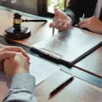 Memuriyetten İhraç Cezasına İtiraz Süreci: Devlet Memurluğundan Çıkarmaya Karşı Hukuki Yollar 1 Devlet memurluğundan çıkarma kararına karşı memuriyetten ihraç cezasına itiraz sürecini, idare mahkemesinde açılacak iptal davası öncesinde avukat ile müvekkil arasında yapılan hukuki danışmanlık görüşmesini, adalet terazisini, mahkeme tokmağını ve dava evraklarını sembolize eden kurumsal ofis görseli.