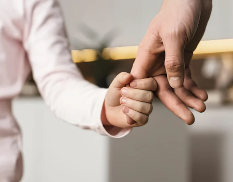 Çocukla Kişisel İlişki Düzenlemesi: Şartları, Süreci ve Güncel Yargıtay Kararları 5 Boşanma veya ayrılık süreci sonrasında velayet hakkı kendisine verilmeyen ebeveynin çocukla kişisel ilişki kurma hakkını, ebeveynlik bağlarının korunmasını ve çocukla geçirilen görüşme zamanlarını sembolize eden; küçük bir çocuğun bir yetişkinin elini sevgiyle tuttuğu kurumsal aile hukuku görseli.