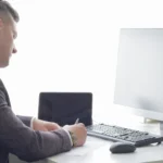E-Tebligat (VUK 107/A): Hak ve Yükümlülükler ile 5 Gün Kuralı 2 Tebligat Kanunu uyarınca UETS üzerinden gönderilen e-tebligat evraklarını inceleyen, tebliğ edilmiş sayılma sürelerini hesaplayan ve bilgisayar başında resmi yasal notlar alan takım elbiseli kurumsal bir avukat veya hukuk danışmanının masaüstü bilgisayar, klavye ve tablet bulunan çalışma ofisindeki yandan profil görünümü.