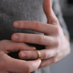 Yurtdışı Boşanma Tanıma Tenfiz Davası: Şartları ve Süreci 1 Yabancı ülke mahkemelerinde gerçekleşen boşanmaların Türkiye'de de geçerli olması amacıyla yürütülen yurtdışı boşanma tanıma tenfiz işlemlerini ve evlilik birliğinin hukuken sona ermesini sembolize eden; parmağındaki altın alyansı/evlilik yüzüğünü çıkaran bir kişinin ellerini yakından gösteren kurumsal boşanma hukuku görseli.