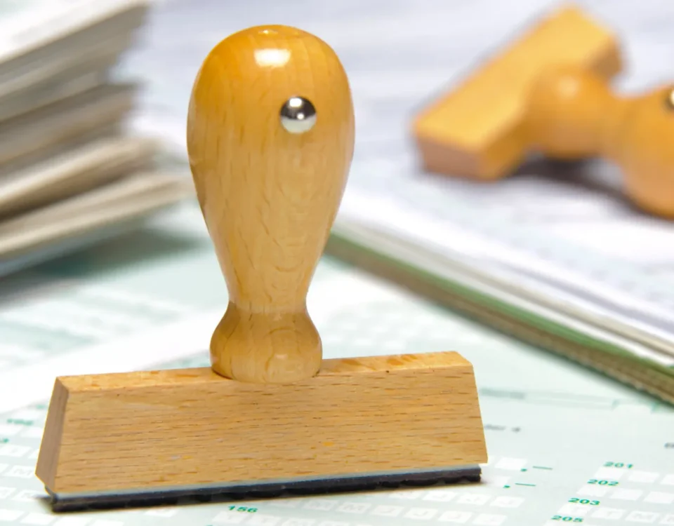 Resmi formlar ve evraklar üzerinde duran ahşap onay kaşesi; İstanbul'da satılan ürünler için düzenlenen geçerli ve onaylı garanti belgesi sürecini temsil eder.
