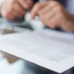 Masa üzerinde duran ve bir uzman tarafından dikkatle okunan resmi sözleşme metni; İstanbul'da tüketicilere sunulan matbu evraklardaki hukuka aykırı maddelerin tespiti için yapılan haksız şart denetimi sürecini temsil eder.