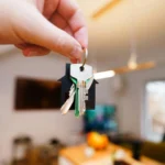 Ev şeklinde anahtarlığa bağlı konut anahtarlarını tutan bir el; İstanbul'da kiralık taşınmazların boşaltılması sonrasında kiracının tahliyesi ve anahtar teslim tutanağı düzenlenme sürecini temsil eder.
