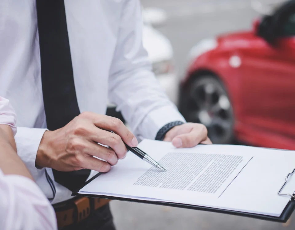 Kırmızı bir otomobilin önünde elindeki resmi evrakı göstererek açıklama yapan uzman; İstanbul'daki trafik kazaları sonrasında sigorta şirketleriyle yaşanan uyuşmazlıklarda sigorta tahkim komisyonu başvurusu sürecini temsil eder.